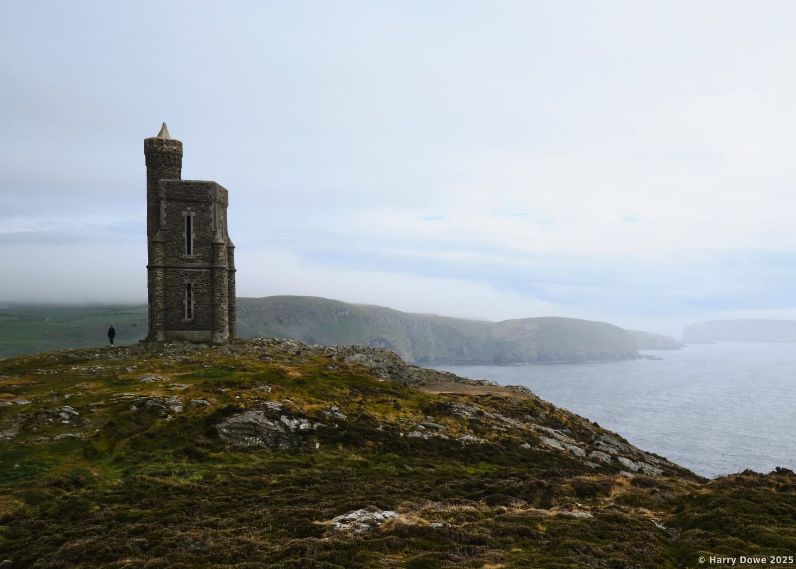Milner's Tower atop a rocky outcrop, overlooking the tranquil coast below.