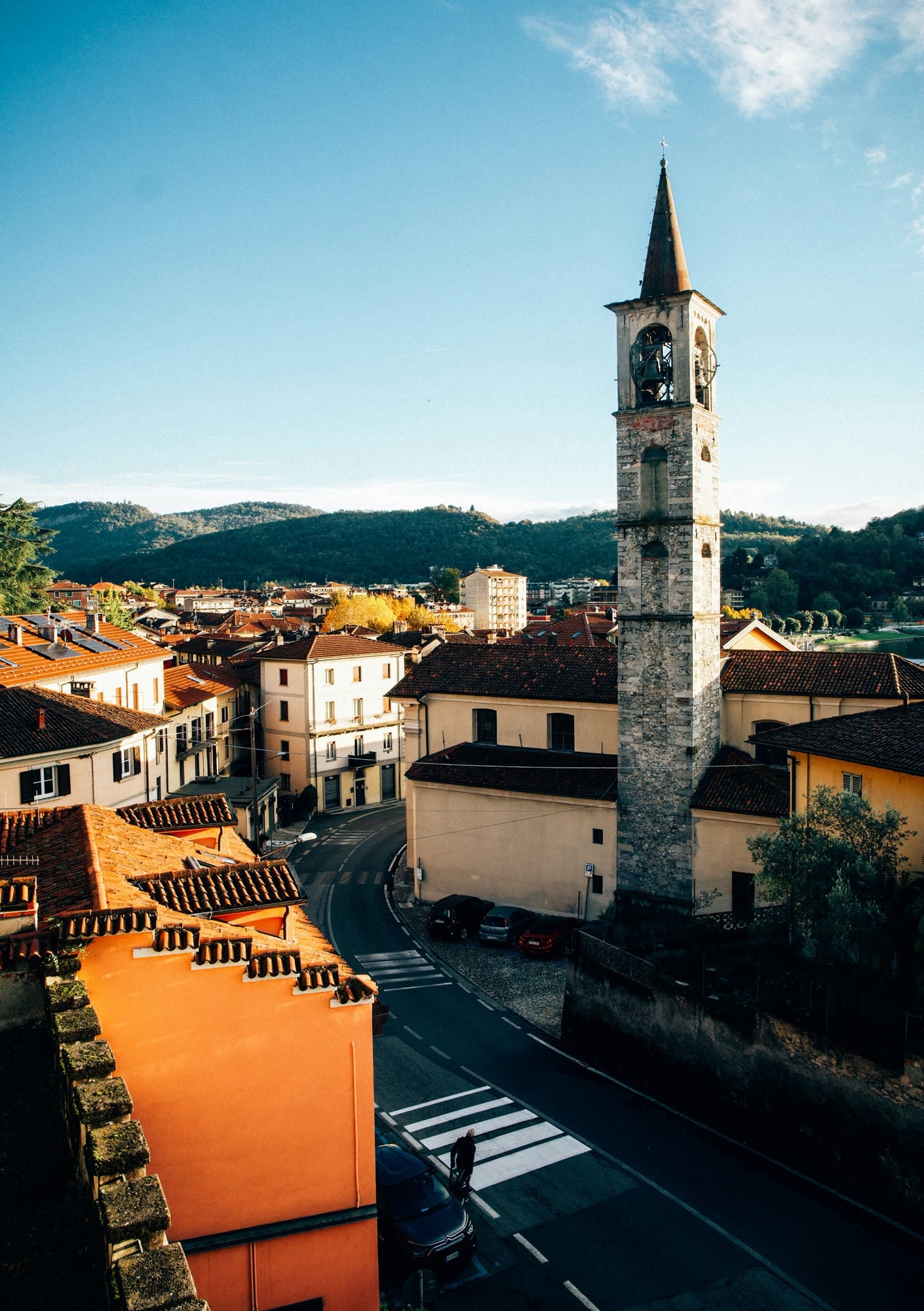 A stone bell tower rising above warm tiled rooftops beneath a clear blue sky.